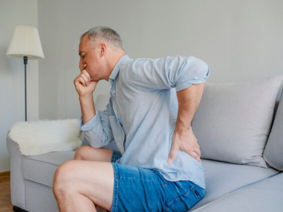 Dr. Giovanni Marchini Urologista - Sinais de Pedra nos Rins que nao devem ser ignorados - homem de meia idade sentado no sofa com dor nos rins